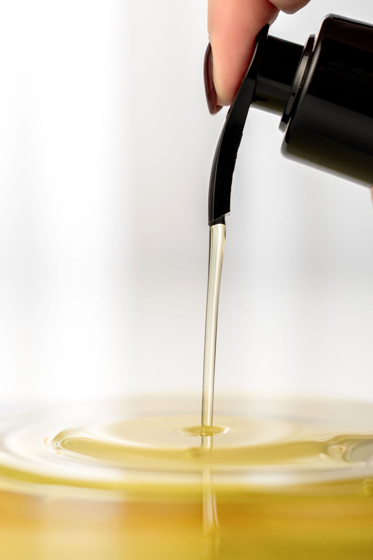 Golden borage and frankincense cleansing oil dispensed from a pump bottle, showing its silky texture